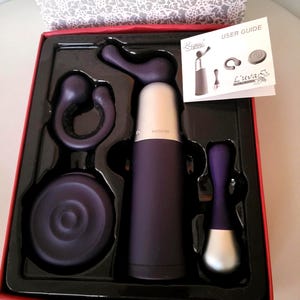 Op de afbeelding: Een wijnopener set in een rode doos met een patroon op het deksel. De set bevat een paarse en zilveren kurkentrekker, een flesstopper en andere wijnaccessoires. Een gebruikershandleiding is ook inbegrepen.