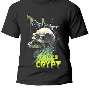 Peut inclure: T-shirt noir avec un motif vert et blanc représentant la tête d'un monstre et le texte "Tales from the Crypt".