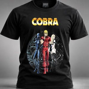 Peut inclure: Un t-shirt noir à manches courtes avec le mot COBRA en lettres jaunes audacieuses au-dessus d'un graphique circulaire. L'illustration représente trois personnages de style anime en tenues rouge, bleue et blanche sur un fond de lignes blanches.