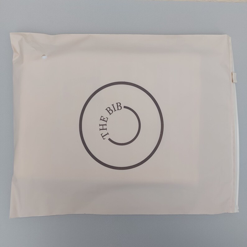 May include: A white mailing envelope with a brown circle logo that says "THE BIB" in a circular font.