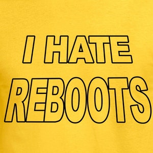 Może przedstawiać: Żółta koszulka z napisem "I HATE REBOOTS" w pogrubionych czarnych literach. Tekst jest wyśrodkowany na przodzie koszulki. Koszulka wykonana jest z jednolitego żółtego materiału, prawdopodobnie bawełny lub podobnego materiału.