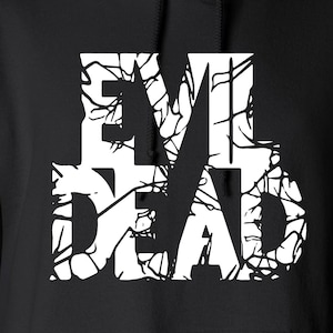 May include: Black hoodie featuring the white text "EVIL DEAD" in a distressed, cracked design. The sweatshirt has a drawstring hood and a front pocket. The brand name "Gildan" is visible on the tag.