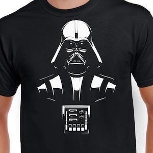 Könnte beinhalten: Ein schwarzes T-Shirt mit einer weißen Silhouette von Darth Vader aus Star Wars. Das Bild zeigt Vaders Helm, Gesicht und Brustpanzer. Der Text "Darth Vader" ist unter dem Bild gedruckt.