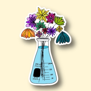 May include: A colorful bouquet of flowers in a blue glass beaker with markings for measuring liquids. The beaker is labeled "PYREX" and has a capacity of 250 ml.