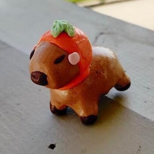 Escultura de capibara con sombrero naranja