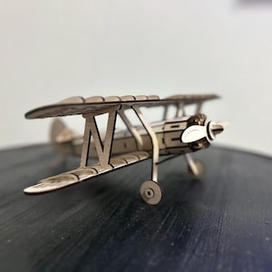 Op de afbeelding: Een houten model van een vintage biplane met een propeller. Het model is gemaakt van lichtbruin hout en heeft een gedetailleerd ontwerp.
