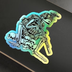 Könnte beinhalten: Ein Aufkleber mit einem Skelettsoldaten, der ein Gewehr hält und einen Helm trägt. Das Skelett ist von Schädeln umgeben und hat einen Regenbogen-Farbverlauf im Hintergrund.