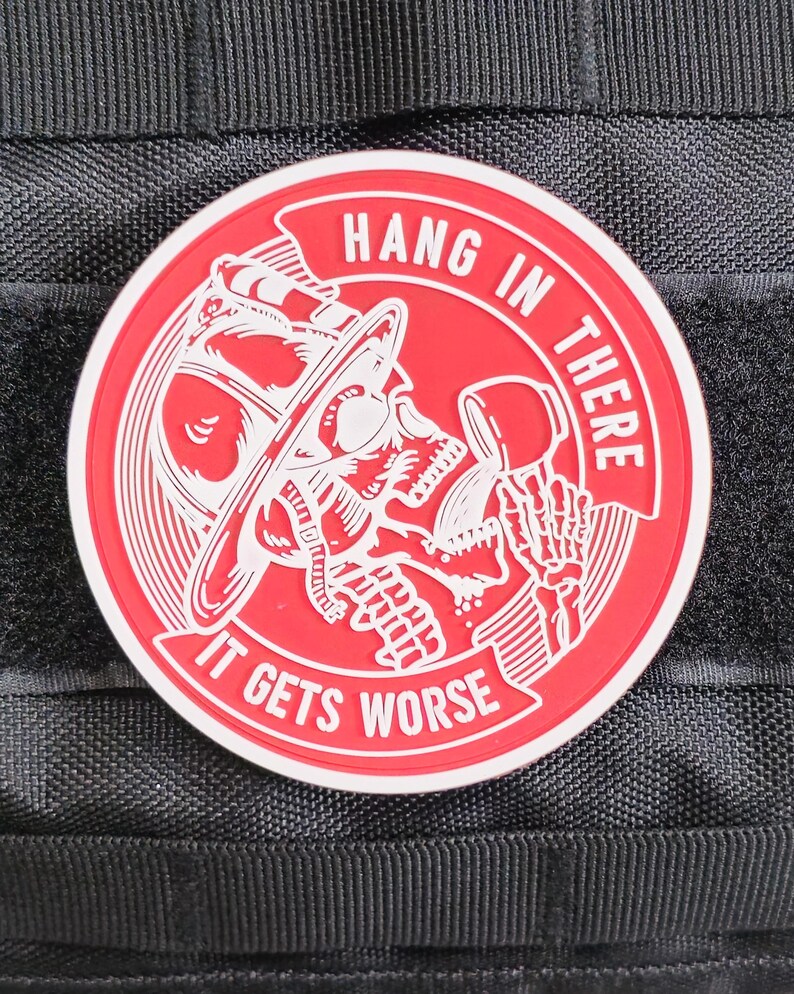 May include: Red and white embroidered patch with a skull wearing a firefighter's helmet and holding a phone. The text reads "Hang in there it gets worse".