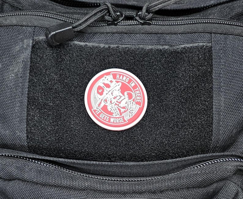 May include: A black tactical backpack with a red and white patch that says "Hang in there it gets worse".