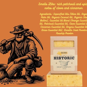 May include: A bar of soap from the Historic Soap Company, with a gold rush theme. The soap is in a cardboard box with the company name and a small illustration. The image also features a drawing of a miner.