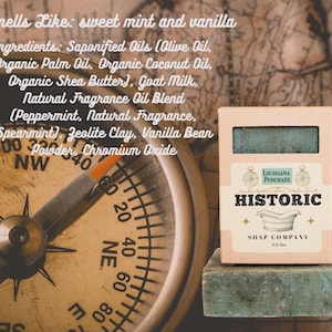May include: A bar of green soap and its box from the Historic Soap Company, with the text "Louisiana Purchase" and "Historic" on the box. The soap smells like sweet mint and vanilla. A compass is in the background.