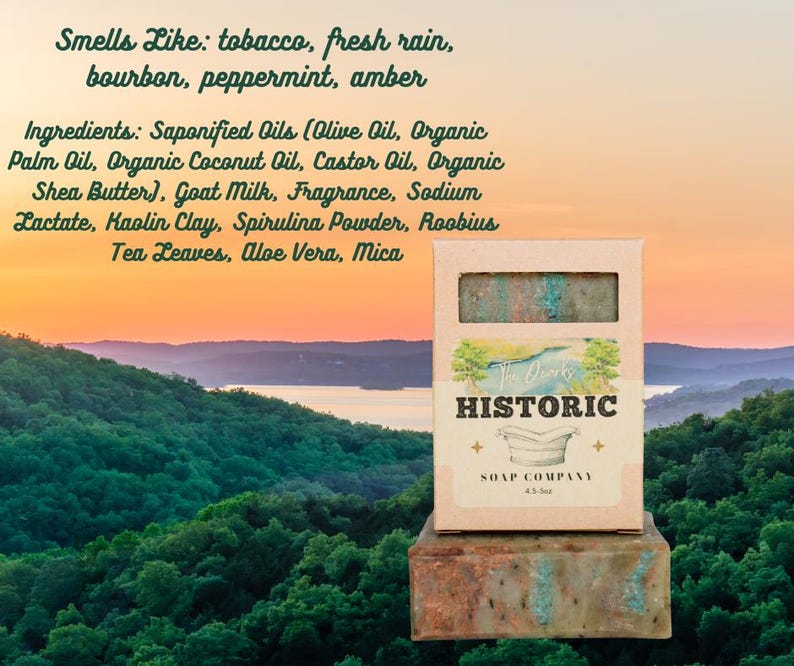 May include: A bar of soap in a cardboard box with the text "Historic Soap Company." The soap is green and brown, with a view of a lake and mountains in the background. The text on the box says the soap smells like tobacco, fresh rain, bourbon, peppermint, and amber.