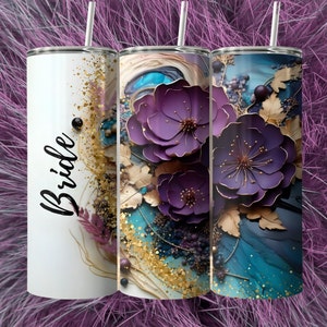 May include: Three stainless steel tumblers with a floral design. The tumbler on the left has the word "Bride" written on it. The tumblers have a purple, gold, and blue design with glitter accents.