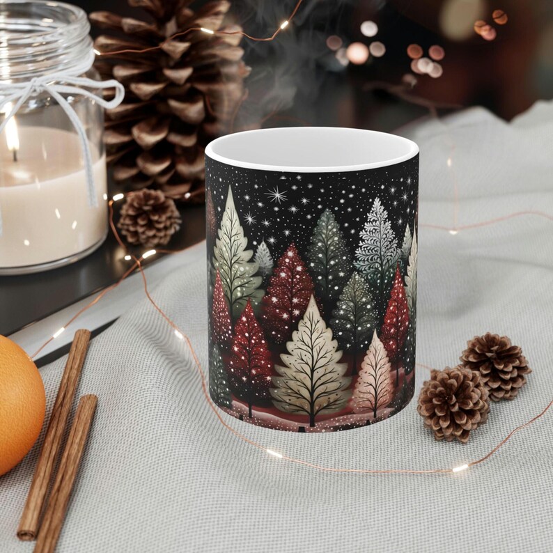 May include: A white ceramic mug with a black background and a colorful illustration of a winter forest scene with trees and stars.