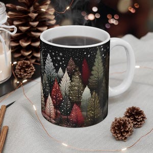 May include: White ceramic mug with a black background and a colorful illustration of a forest scene with trees and stars. The mug is filled with coffee.