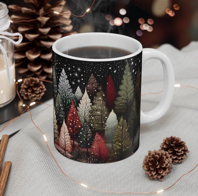 May include: White ceramic mug with a black background and a colorful illustration of a forest scene with trees and stars. The mug is filled with coffee.