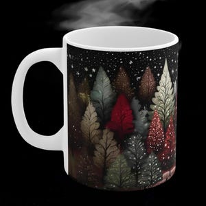 May include: White ceramic mug with a black background and a design of a forest of trees with different colors, including red, green, and brown. The trees are silhouetted against a dark background with white snowflakes.