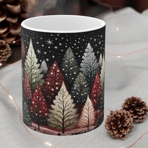 May include: White ceramic mug with a black background and a winter forest scene. The trees are decorated with red, green, and white lights and snow. The mug is perfect for hot beverages.