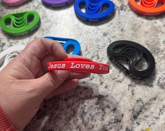 various colors of bracelets that say Jesus Loves You