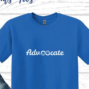 Peut inclure: Un t-shirt bleu royal avec le mot "Advocate" imprimé en blanc avec un symbole d'infini remplaçant le "O". Le t-shirt est présenté sur un mannequin avec un jean bleu et des baskets noires.