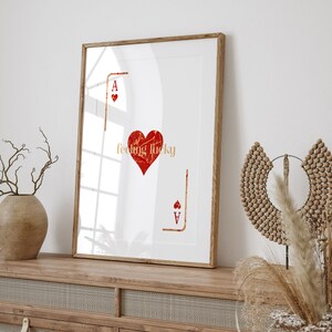 Peut inclure: Une impression encadr&eacute;e avec un fond blanc et un c&oelig;ur rouge avec le texte "feeling lucky" &agrave; l'int&eacute;rieur. Le c&oelig;ur est entour&eacute; d'un contour noir et le texte est en police dor&eacute;e. L'impression pr&eacute;sente &eacute;galement l'as de pique de carte &agrave; jouer dans le coin inf&eacute;rieur droit.