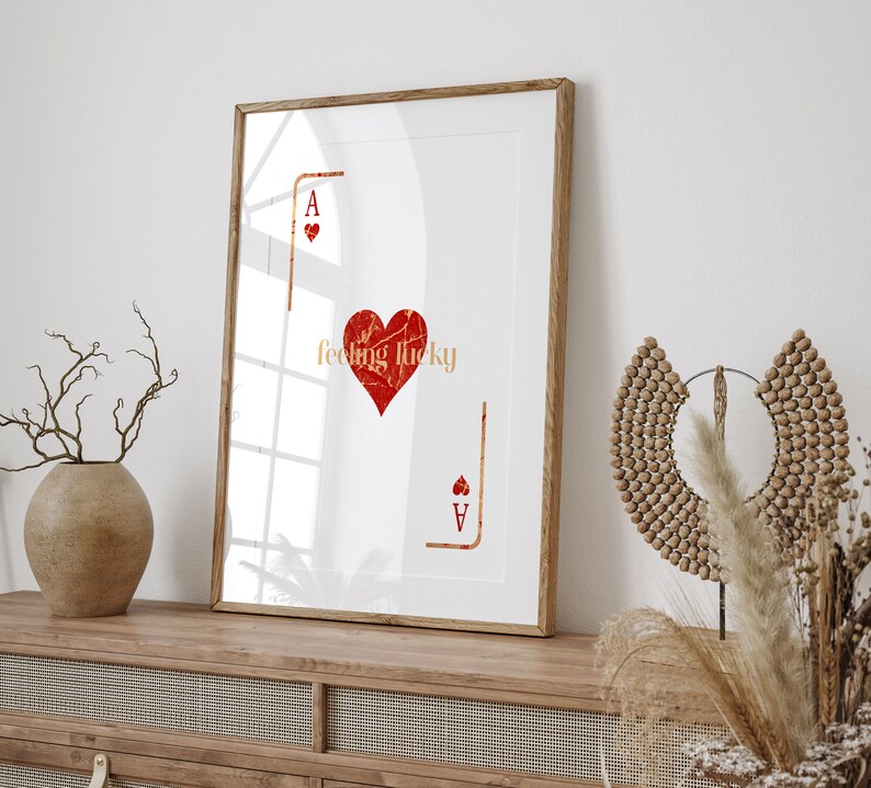 Peut inclure: Une impression encadr&eacute;e avec un fond blanc et un c&oelig;ur rouge avec le texte "feeling lucky" &agrave; l'int&eacute;rieur. Le c&oelig;ur est entour&eacute; d'un contour noir et le texte est en police dor&eacute;e. L'impression pr&eacute;sente &eacute;galement l'as de pique de carte &agrave; jouer dans le coin inf&eacute;rieur droit.