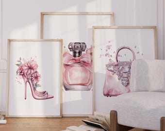 May include: Three framed prints with a pink and white watercolor design. The prints feature a high-heeled shoe with flowers, a bottle of perfume, and a handbag with rhinestones.
