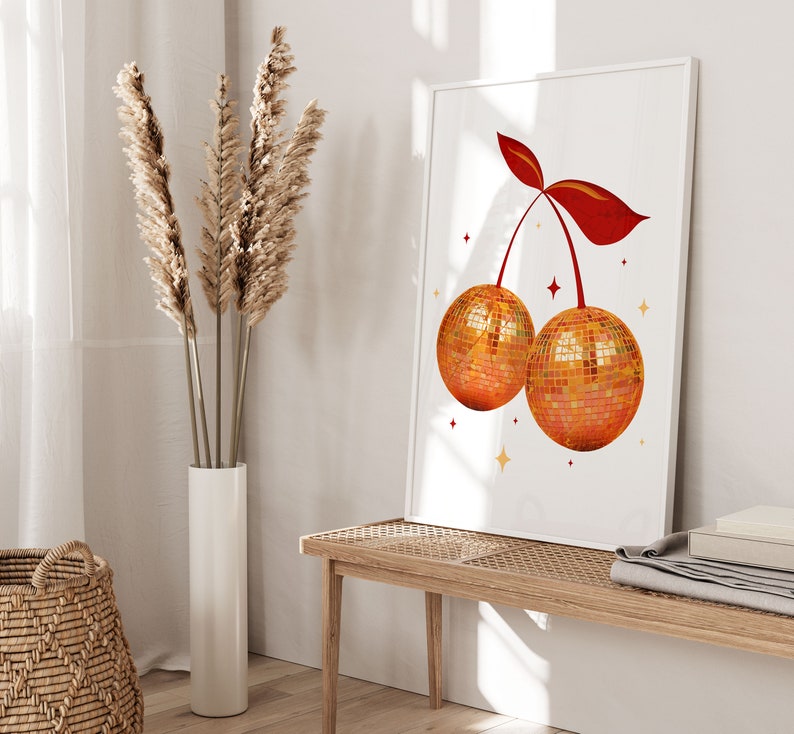 Peut inclure: Une impression encadr&eacute;e blanche avec un motif de cerise rouge. La cerise est compos&eacute;e de deux boules disco. L'arri&egrave;re-plan est blanc avec des &eacute;toiles dor&eacute;es.