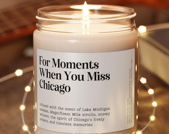 Könnte beinhalten: Eine brennende Kerze in einem durchsichtigen Glas mit einem weißen Etikett mit der Aufschrift "For Moments When You Miss Chicago". Die Kerze steht auf einem kleinen, runden Untersetzer aus Holz. Lichterketten und eine Gitarre sind im Hintergrund.
