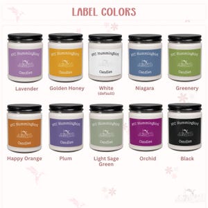 Op de afbeelding: Een verzameling glazen potkaarsen met zwarte deksels en kleurrijke etiketten. De etiketten tonen de tekst "NYC Hummingbird Candles" en verschillende kleurnamen zoals Lavendel, Golden Honey en Zwart. De tekst "LABEL COLORS" staat bovenaan.
