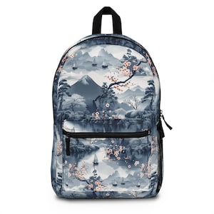 May include: A backpack featuring a Japanese landscape design. The design includes a mountain, lake, boats, and cherry blossoms in blue, grey, and pink. The backpack has a black handle, zip, and a front pocket.