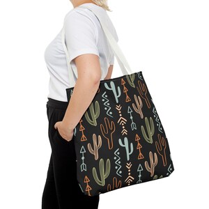 May include: A black tote bag with a white handle and a repeating pattern of green, blue, and orange cacti and arrows.