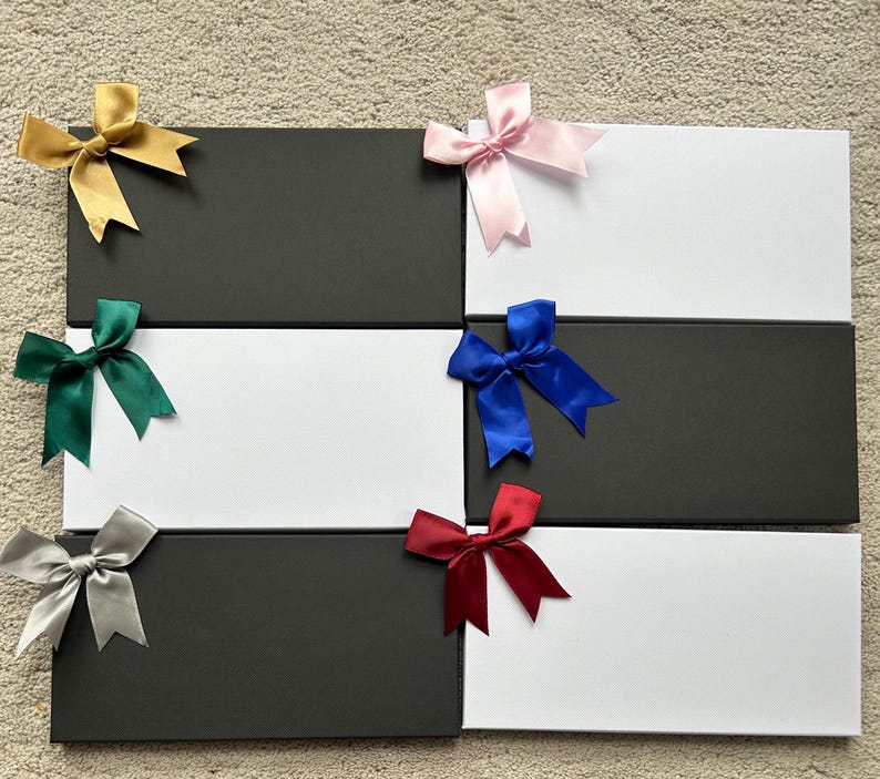 May include: Six black and white gift boxes with different colored bows. The bows are gold, pink, green, blue, red, and silver.