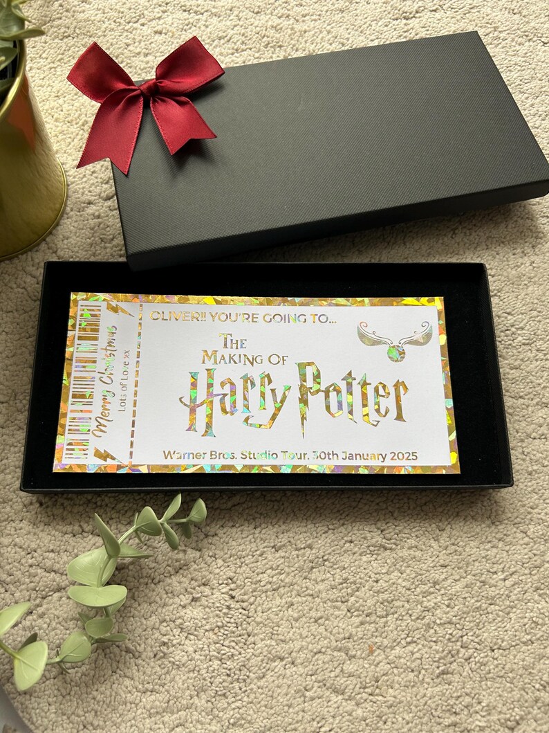 May include: A gold and white ticket with the text "OLIVER!! YOU'RE GOING TO... THE MAKING OF Harry Potter Warner Bros. Studio Tour. 30th January 2025" and a graphic of a golden snitch.