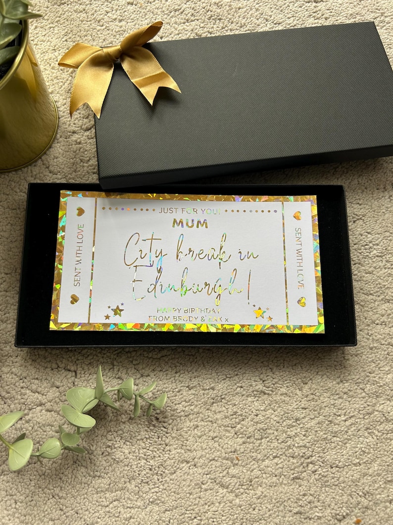 May include: A gold and white gift card with a holographic finish. The card says "Just for you! Mum City break in Edinburgh! Happy Birthday! From Brody & Amy x".