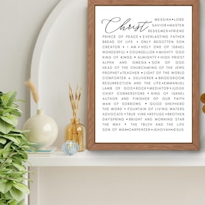 以下が含まれることがあります： 白い背景と黒いテキストで額装されたプリント。テキストには「キリスト」と、イエス・キリストの多くの称号と説明が書かれており、「メシア」、「主」、「救世主」、「師」、「贖い主」、「友」、「平和の君主」、「永遠の父」、「命のパン」、「独り子」、「創造主」、「私はある」、「イスラエルの聖なる者」、「素晴らしいカウンセラー」、「全能の神」、「王の王」、「全能者」、「大祭司」、「アルファとオメガ」、「神の子」、「教会の頭」、「ユダヤ人の王」、「預言者」、「教師」、「世界の光」、「慰め主」、「解放者」、「新郎」、「復活と生命」、「エマヌエル」、「神の子羊」、「岩」、「仲介者」、「裁判官」、「礎石」、「イスラエルの王」、「信仰の著者と完成者」、「悲しみの男」、「良い羊飼い」、「言葉」、「生きた水の泉」、「擁護者」、「真のブドウの木」、「避難所」、「兄弟」、「夜明け」、「明るい朝の星」、「道」、「真理と生命」、「人の子」、「大工」、「ヤハウェイエス」が含まれています。