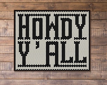 May include: A brown leather couch with a brown throw pillow in front of a wooden wall with a black and white mosaic tile art piece that says "Howdy Y'all".