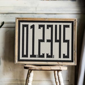 May include: A framed black and white mosaic art piece with the number "1215" displayed in a geometric pattern.