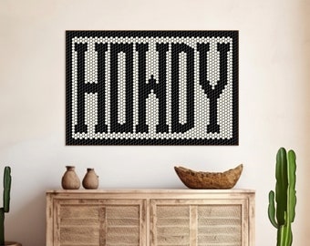 May include: A black and white mosaic art piece with the word "HOWDY" displayed on a wall. The artwork hangs above a wooden cabinet with woven panels. Two small brown vases and a wooden bowl are on the cabinet.