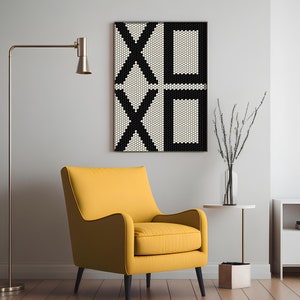 Könnte beinhalten: Ein gelber Sessel mit schwarzem Gestell steht vor einer weißen Wand mit einem schwarz-weißen geometrischen Druck, der an der Wand hängt. Eine goldene Stehlampe befindet sich im Hintergrund.