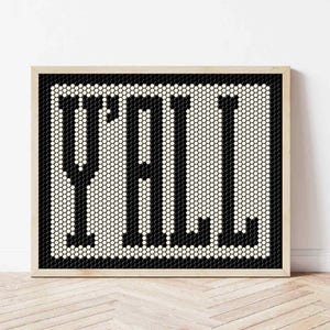 May include: A framed art print with the word "Y'ALL" in bold, black letters. The letters are composed of small, black hexagonal tiles against a white background. The frame is a light wood color.