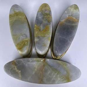 May include: Four oval-shaped, light blue and gold marble drawer pulls with a brass finish.