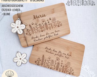 Puede incluir: Dos tablas de cortar de bambú con diseños florales y el texto "Maria" y "Danke, dass Du uns beim Wachsen geholfen hast." Un adorno de madera en forma de flor está unido a una tabla. Las tablas son para profesores.