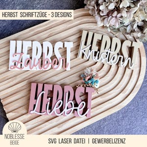 Könnte beinhalten: Drei Holzschilder mit dem Wort "HERBST" in Großbuchstaben, jedes mit einem anderen Wort in Schreibschrift: "Zauber", "Knistern" und "Liebe". Die Schilder sind in Weiß, Beige und Rosa gehalten. Der Text "HERBST SCHRIFTZÜGE - 3 DESIGNS" steht oben.