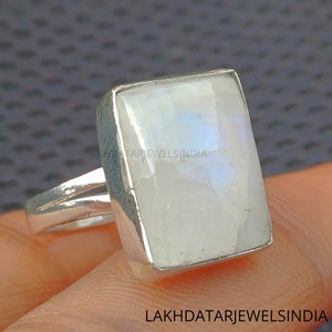 May include: A silver ring with a large, rectangular, white moonstone. The ring has a double band.