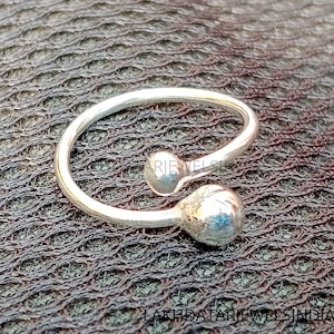 Op de afbeelding: Een zilveren teenring met twee ronde ballen. De ring is open en kan worden aangepast aan verschillende maten.