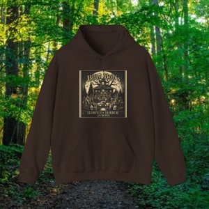 Puede incluir: Sudadera con capucha marrón con un estampado gráfico de una casa espeluznante con un árbol y el texto "Bill & Bob's Eldritch Horror Jamboree".