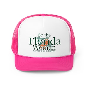 Puede incluir: Gorra de camionero rosa y blanca con un contorno verde y blanco de Florida y el texto "Be the Florida Woman You wish to see in the world".