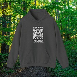 May include: A dark gray hooded sweatshirt with a white graphic print that says "Any room can be a panic room if you give me a second". The graphic features a stick figure in a room with bars on the windows.