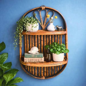 May include: A brown rattan wall shelf with two levels, holding plants, books, and decorative items. The shelf has an oval shape with a decorative top and is mounted on a blue wall. The shelf contains a white vase with yellow flowers.